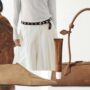 Stylish person confidently walking down the street wearing a tailored outfit, accessorized with a statement bag and elegant footwear, showcasing modern fashion trends